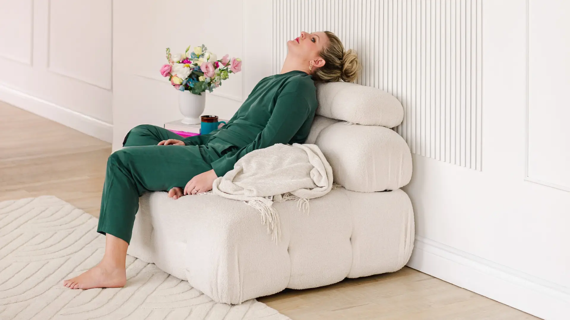 Libby Ward slouches on a sofa with a look of defeat on her face as she is experiencing overstimulation as a mom.