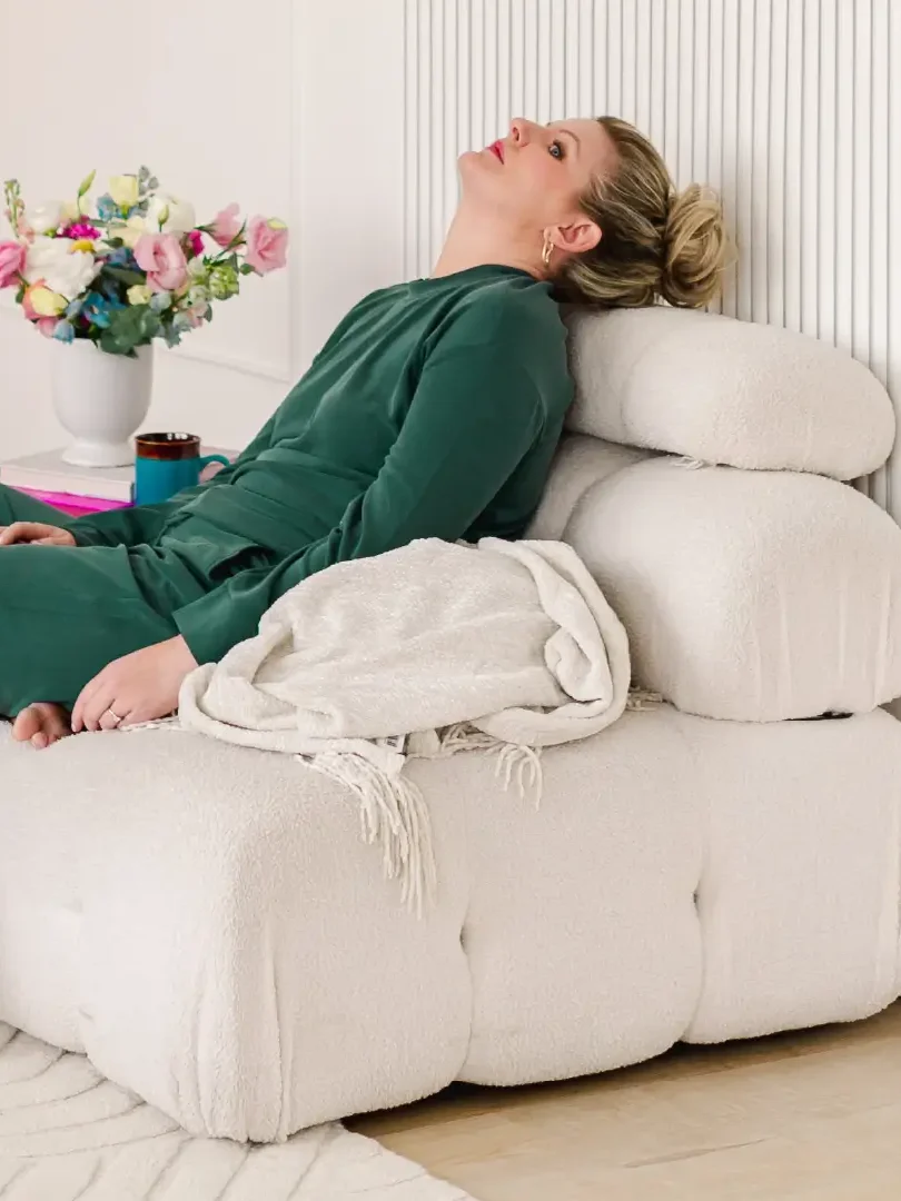 Libby Ward slouches on a sofa with a look of defeat on her face as she is experiencing overstimulation as a mom.